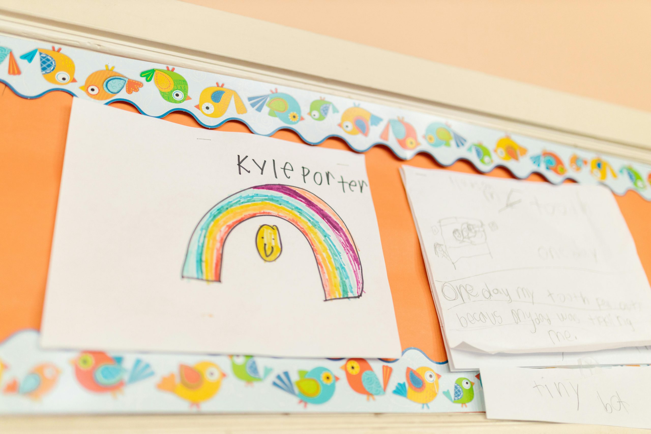 Vibrant children's drawings hang on a decorated classroom wall.